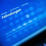 Auf dem Bildschirm eines aufgeklappten Laptops steht in weißer Schrift das Wort Fahndungen auf einem blauen Hintergrund. (Symbolbild)