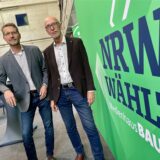 Die beiden HA-Redakteure Harald Landgraf und Joachim Schmidt stehen auf dem Podium der Wahlarena im Medienhaus Bauer, neben dem Schriftzug „NRW wählt“.