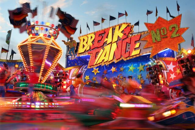 Kirmes-Besucher auf dem Öcher Sommerbend 2025 fahren das Rundfahrgeschäft „Break-Dance – No. 2“ bei Nacht.