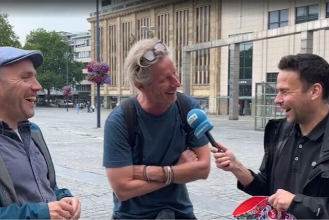 Eine Frau liest in der Dortmunder Innenstadt etwas von einem Zettel ab.