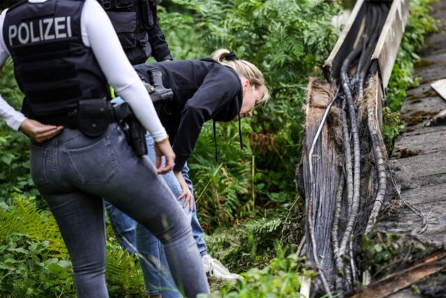 Polizeibeamte der Spurensicherung stehen an einem Gleisabschnitt. Dort wurde neben der Bahnstrecke Feuer in einem Kabeltunnel gelegt, der sechs Kabel in Mitleidenschaft zog.