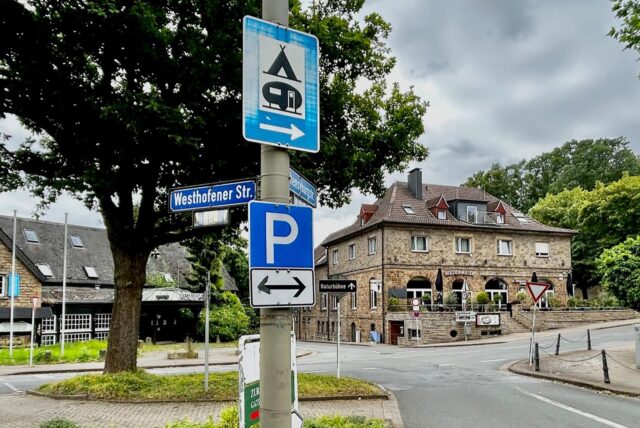 Im Zentrum des Bildes verweist das blaue Parkschild auf den Parkplatz an der Hohensyburg.