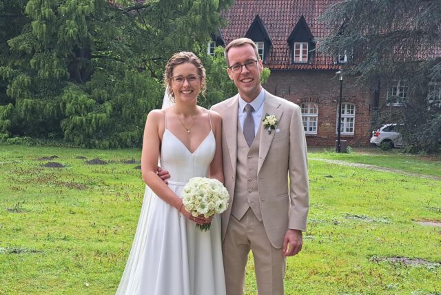 Theresa und Sebastian Himmelseher stehen vor einer Wiese, dahinter das Schloss Herten.