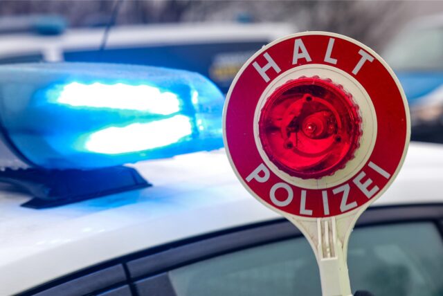 Ein Polizist hält eine Polizeikelle.