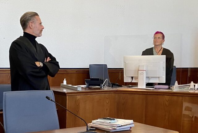 Rechtsanwalt Christian Simonis steht im Gerichtsaal des Landgerichts, daneben eine Kollegin hinter einem Bildschirm.