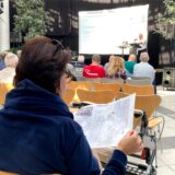 Eine Frau nimmt an der Bürgerinformation zur bevorstehenden Kaiserstraßen-Sperrung im Glashaus teil und blickt auf eine Karte.