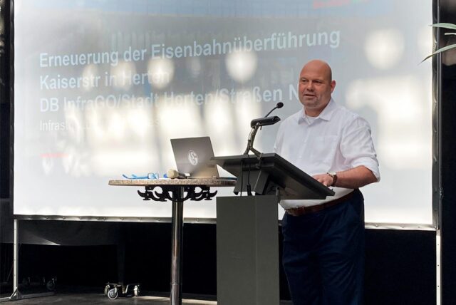 Der Hertener Ordnungsdezernent Dr. Oliver Lind steht im Glashaus an einem Rednerpult und stellt das Bauprojekt Kaiserstraße vor.