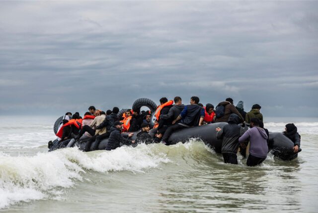 Migranten besteigen das Schlauchboot eines Schmugglers. Dieses Symbolfoto ist am Ärmelkanal entstanden.