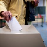 Eine Frau wirft einen Wahlschein in eine Wahlurne.