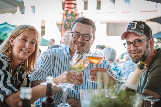 Drei Personen stoßen mit einem Glas Wein auf Bochum kulinarisch an