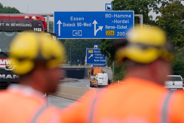 Arbeiter stehen auf der gesperrten Autobahn A40.