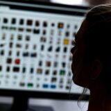 Symbolbild: Eine Frau sitzt vor einem Bildschirm mit hunderten Fotodateien