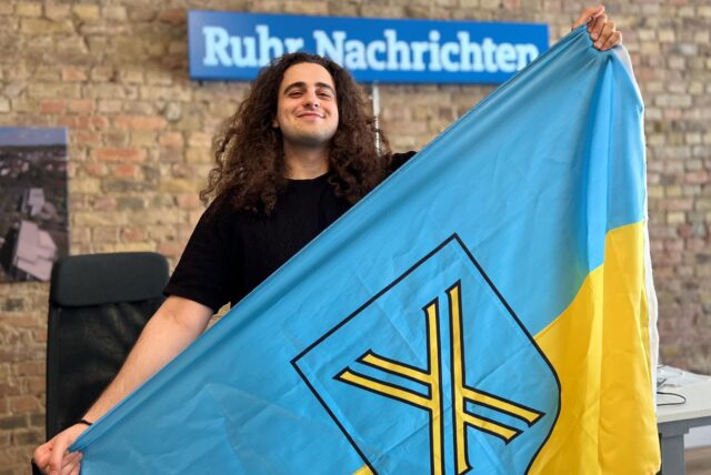 Koray Tokmak hält eine Castrop-Rauxel FLagge in der Redaktion