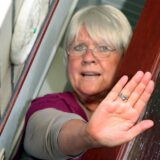 Eine Seniorin macht eine ablehnende Handbewegung an der Haustür.