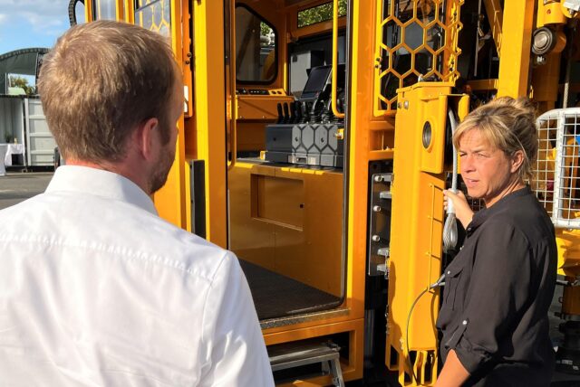 Ministerin Mona Neubaur steht vor einem Fahrzeug der Firma Daldrup und Söhne in Ascheberg und spricht mit Vorstand Bernd Daldrup.