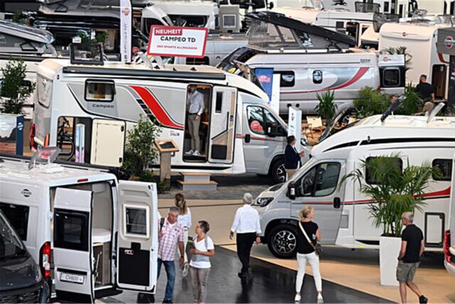 Besucher gehen auf dem Caravan Salon in Düsseldorf zwischen Wohnmobilen.