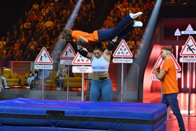 Die Dortmunder Sina Ruppenthal stemmt in der Sat1 Live-Show „Guinness World Records – Die große Show der Weltrekorde“ einen Mann vor einer dicken Matte hoch.