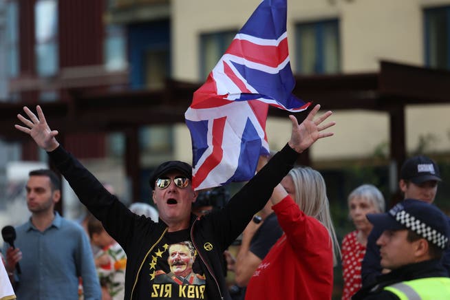 Mitten in London protestieren Unzufriedene gegen die Unterbringung von Migranten in einem Hotel (8. August). Im Bild der im Text erwähnte Mann mit dem Stalin-Leibchen.