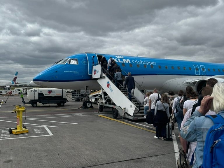 Menschen, die sich anstellen, um einen KLM-Flug auf einer Startbahn zu besteigen