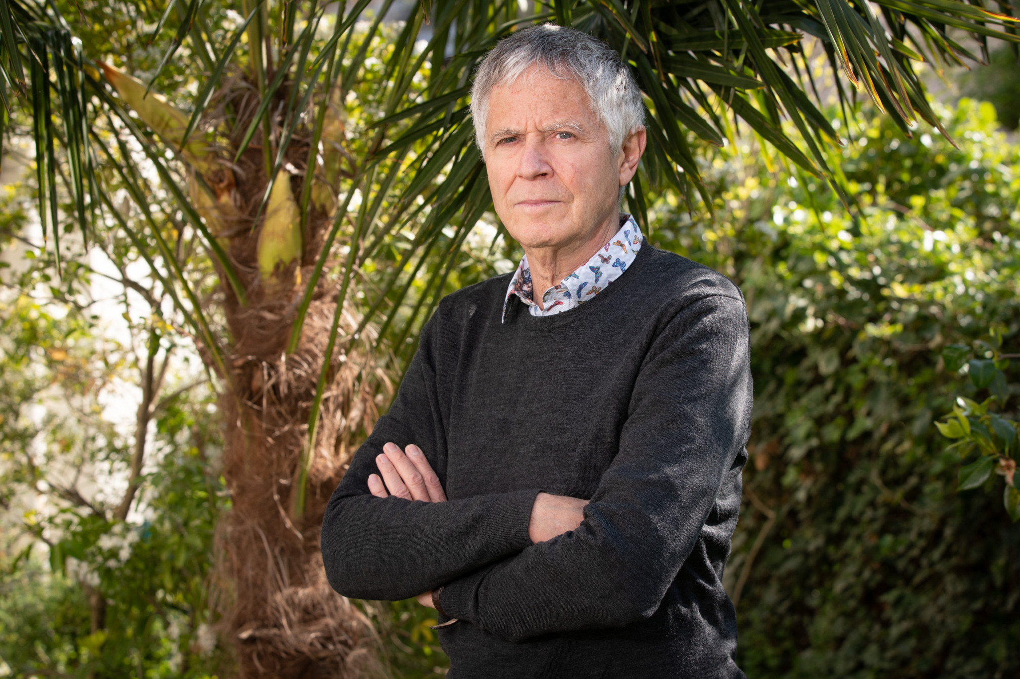 Olivier Legrain steht in seinem Garten in Neuilly-sur-Seine vor einer Palme, mit verschränkten Armen. Er ist bekannt für seinen Einsatz für Migranten.