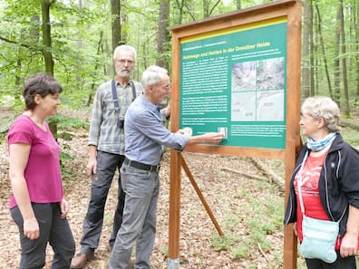Auch diese Tafel zu Hohlwegen und Hohlen - inhaltlich erarbeitet von den Mitgliedern des Arbeitskreises Dresdner Heide - ist neu und leider schon beschmiert. Arbeitskreisleiter Michael Thieme entfernt vorsichtig einen Aufkleber vom QR-Code. Neben ihm stehen Diana Mirtschink sowie  Bernhard Hennig und Martina Glauche (v.l.), die sich vor allem um den Erhalt der historischen Wegezeichen kümmern.