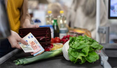 A person holding an open wallet while paying for groceries.