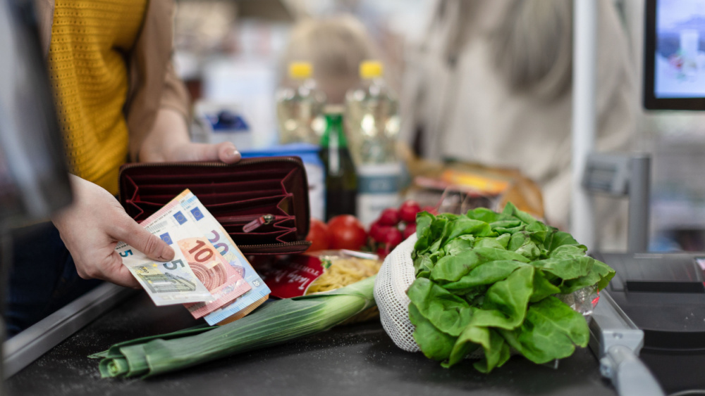 A person holding an open wallet while paying for groceries.