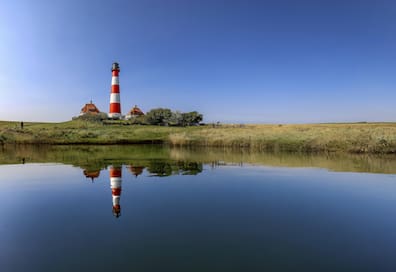 Spiegelungen des Leuchtturms Westerheversand im Wasser.