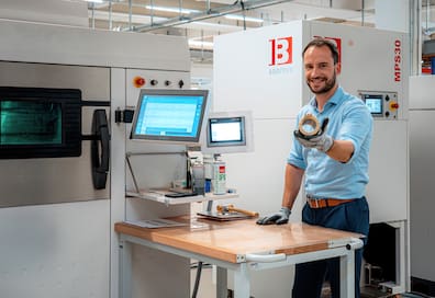 Vertriebs-Geschäftsführer von Additive Drives Philip Arnold zeigt einen Elektromotor, dessen Komponenten teilweise von 3D-Druckern (links im Bild) erzeugt worden sind
