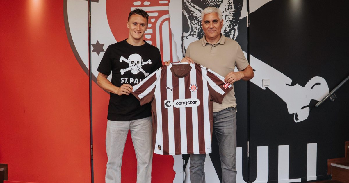 Martijn Kaars und Andreas Bornemann stehen nebeneinander und halten gemeinsam ein St. Pauli-Trikot hoch.