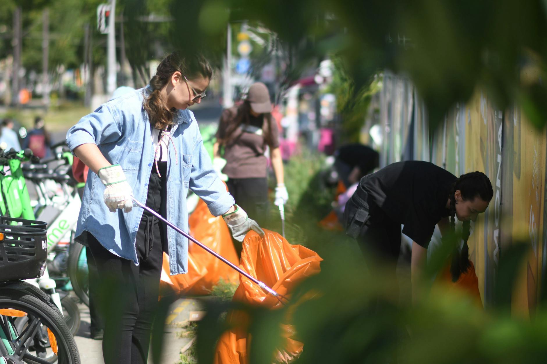 Eine Freiwillige kämpft sich mit der Müllzange die Warschauer Straße entlang und sammelt jeden einzelnen Zigarettenstummel, Plastikfetzen und Papierfetzen auf.