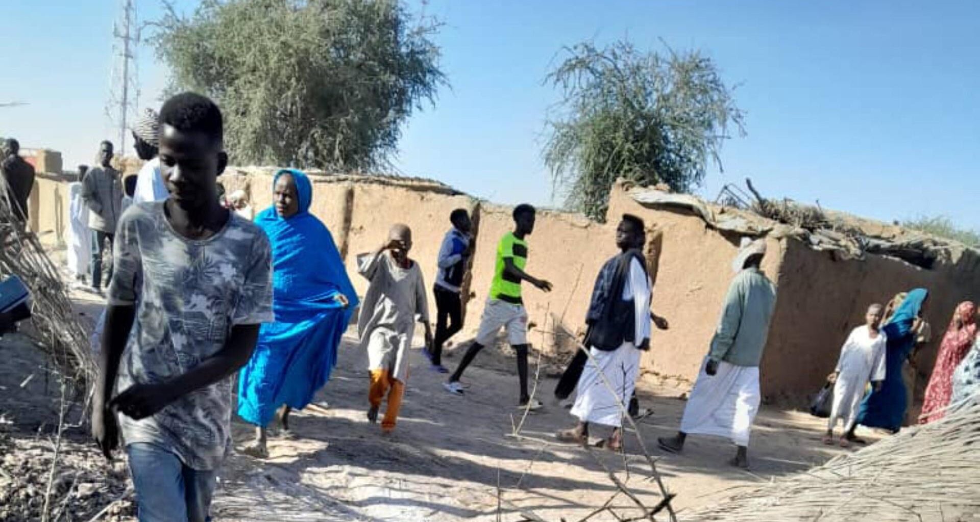 Mehrere Menschen gehen an einer Stelle in Al-Faschir vorbei, an dem ein Anschlag verübt wurde.