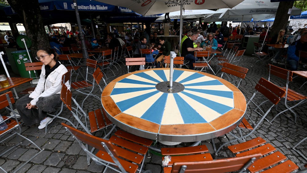 Schutz vor Regen, nicht vor Sonne: Biergartenbesucher unter Schirmen.