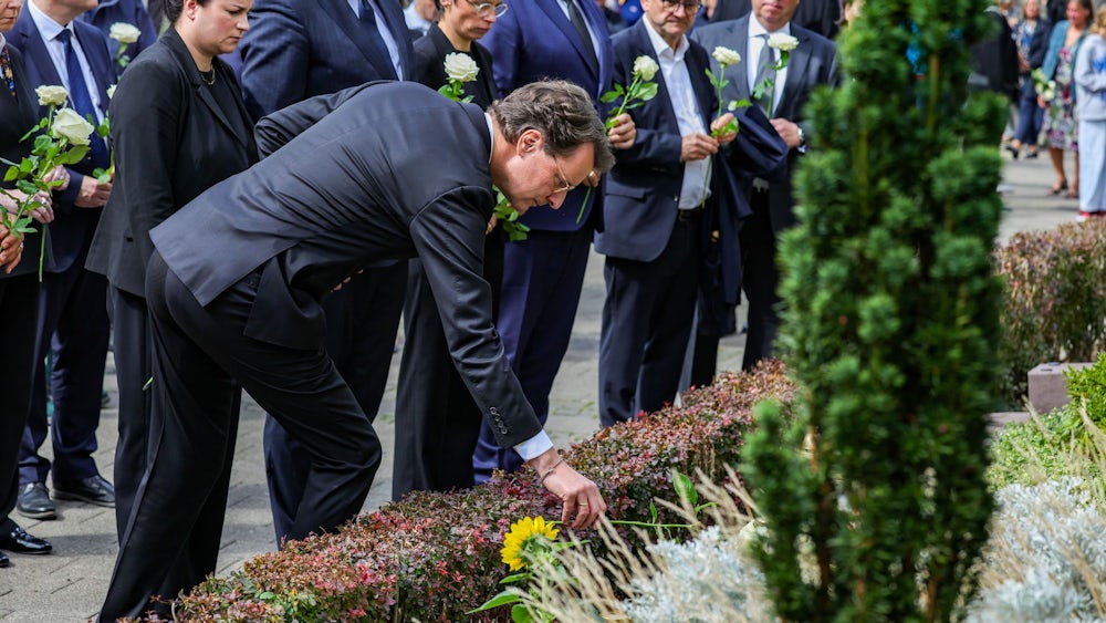 Hendrik Wüst (CDU), Ministerpräsident von Nordrhein-Westfalen, legt eine weiße Rose am Gedenkstein zum Terroranschlag in Solingen ab.