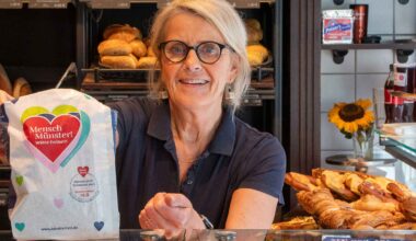 Verkäuferin hält eine Brötchentüte mit Aufdruck in einer Bäckerei