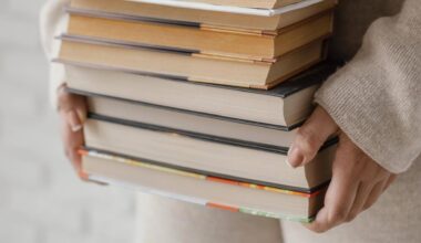Frauenhände halten eine Stapel voller Bücher.