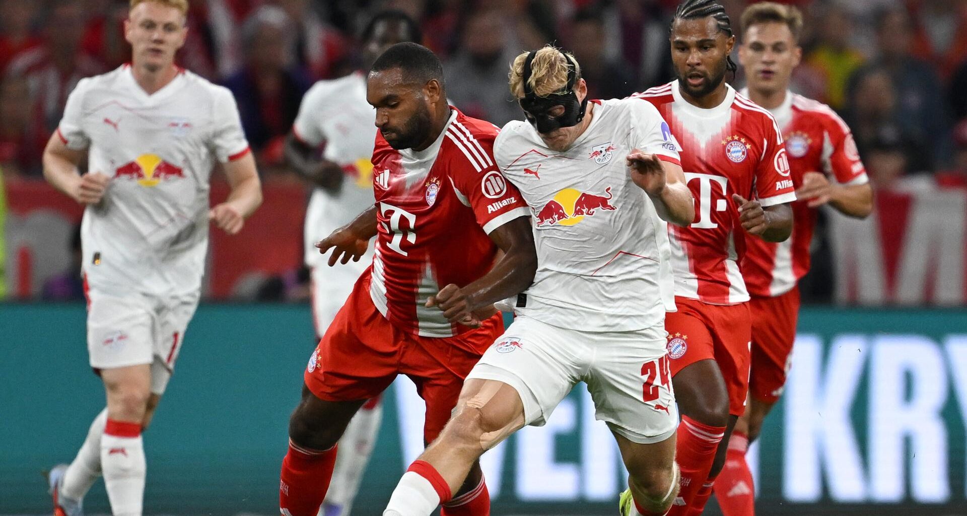 Szene aus dem Bundesliga-Auftaktspiel Bayern München gegen Leipzig; Spieler beider Mannschaften kämpfen um den Ball.