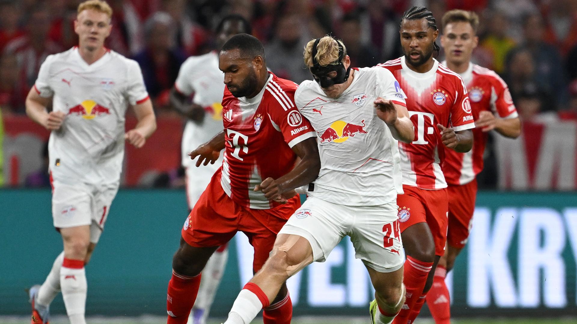 Szene aus dem Bundesliga-Auftaktspiel Bayern München gegen Leipzig; Spieler beider Mannschaften kämpfen um den Ball.