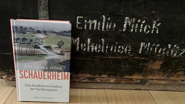 Buch auf der Kiste, mit der der Autor als Kind zusammen mit seiner Mutter und seinen zwei Brüdern aus dem Sudetenland floh und im fränkischen Schauerheim ankam.  | Bild: BR / Dirk Kruse