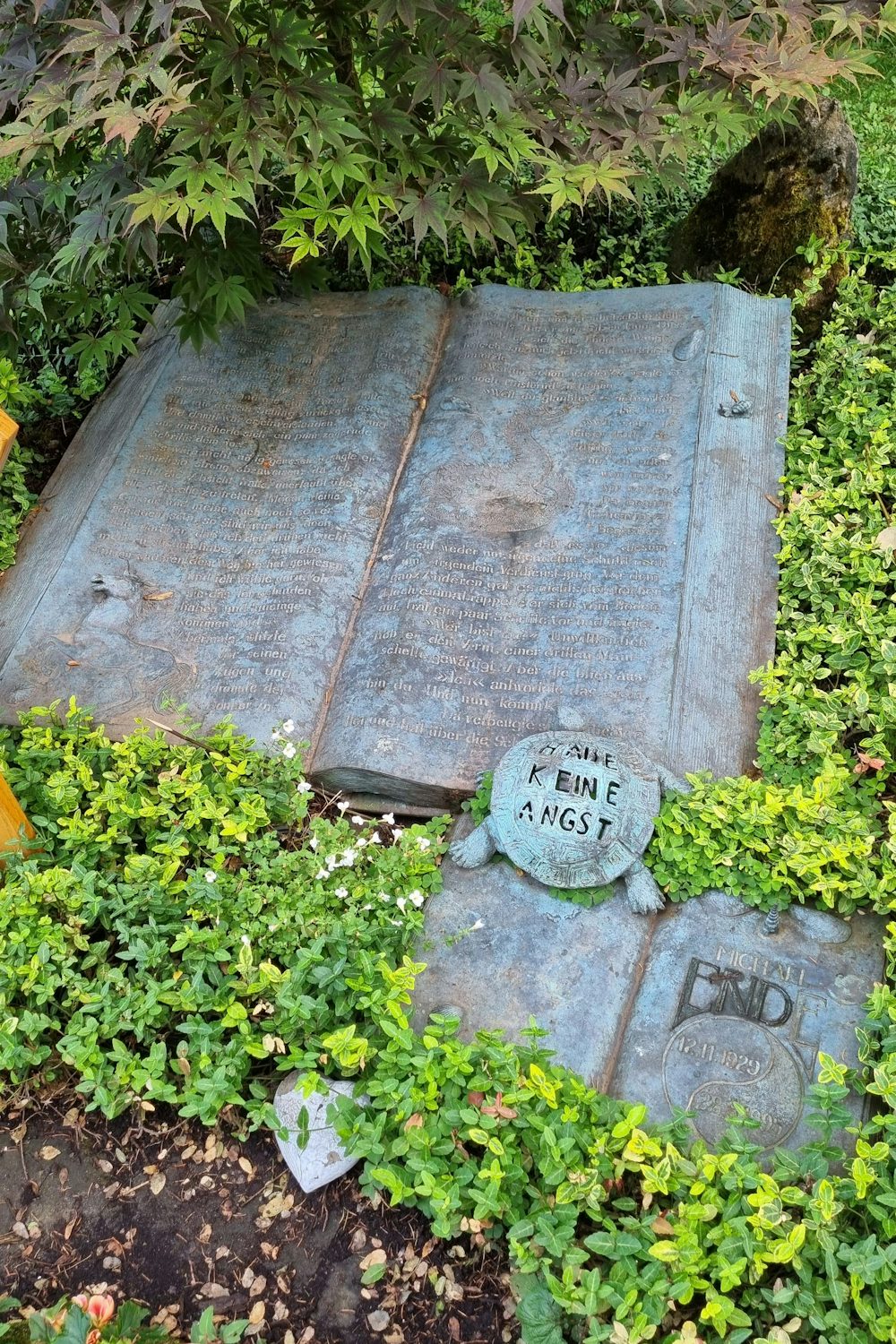 Figuren aus seinen Werken zieren das Grab des Kinderliteraten Michael Ende auf dem Münchner Waldfriedhof.