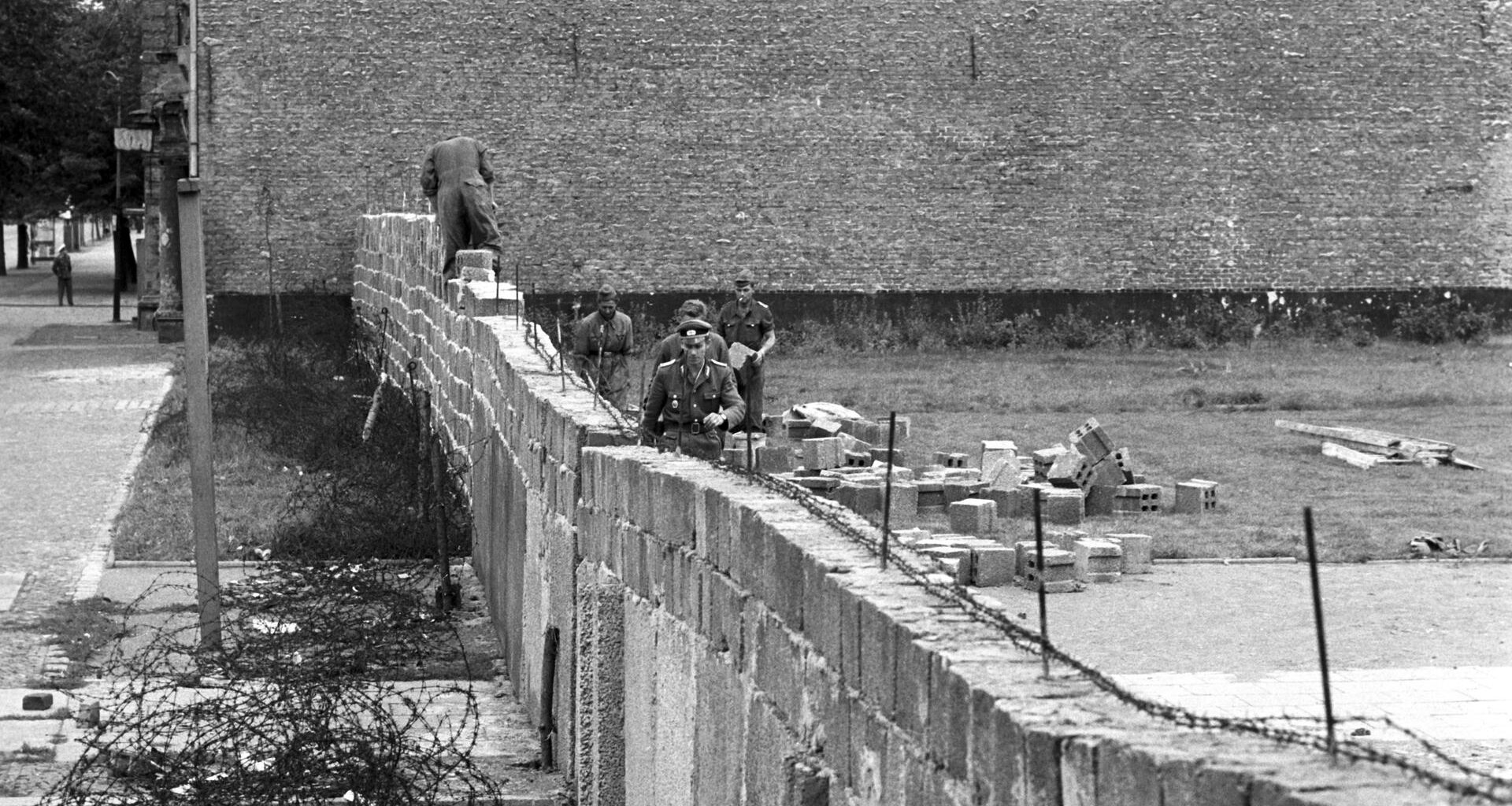 Volkspolizisten und Arbeiter der DDR beim Errichten der Berliner Mauer im Norden Berlins, an der Grenze zum westberliner Bezirk Reinickendorf.