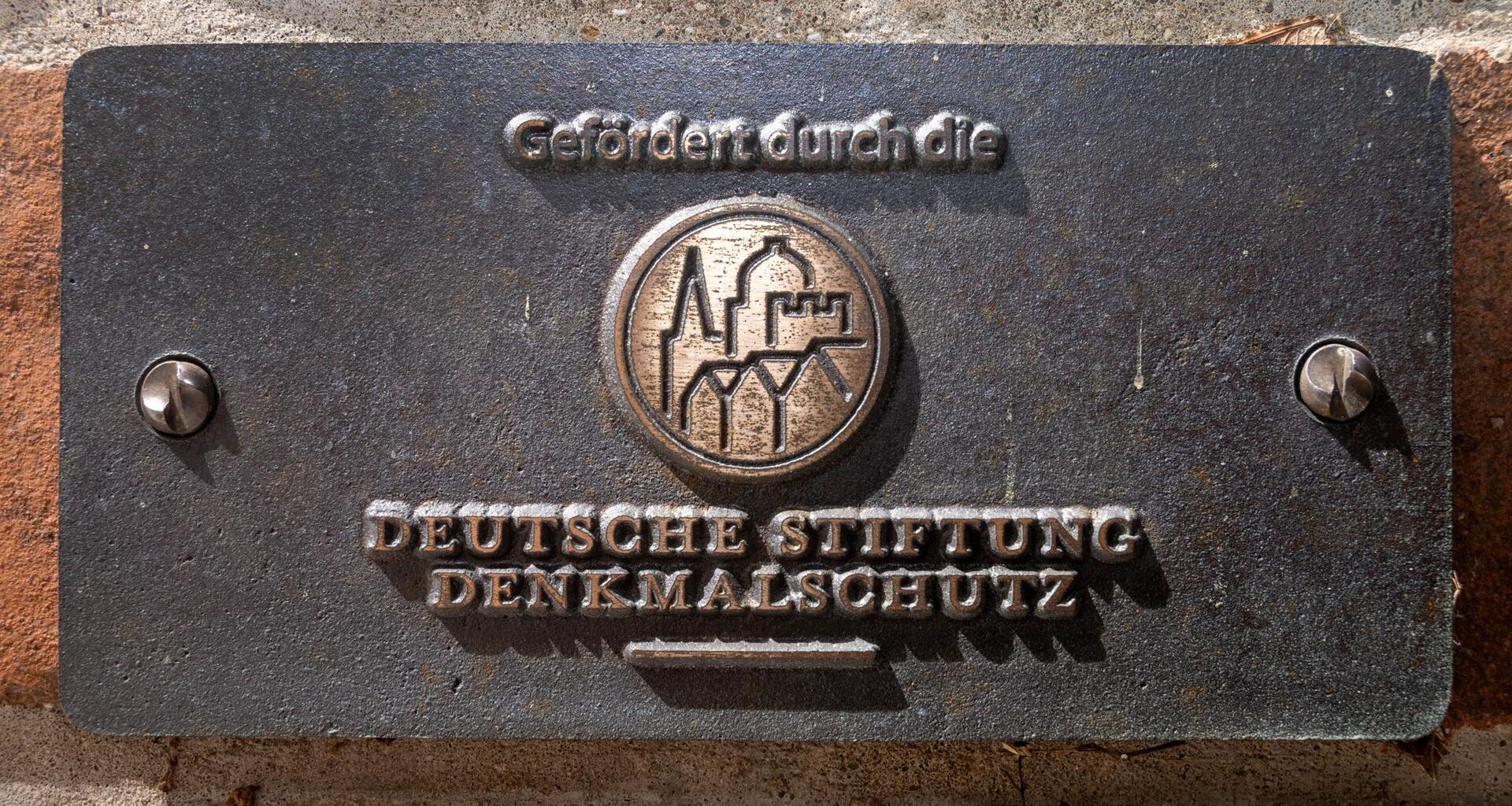 Ein Schild mit dem Schriftzug "Gefördert durch die Deutsche Stiftung Denkmalschutz" hängt im Eingangsbereich des evangelischen Dom St. Nikolai.