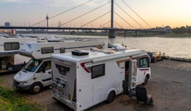 Ein Wohnmobil-Stellplatz am Rheinuferr in Düsseldorf, im Hintergrund eine Brücke