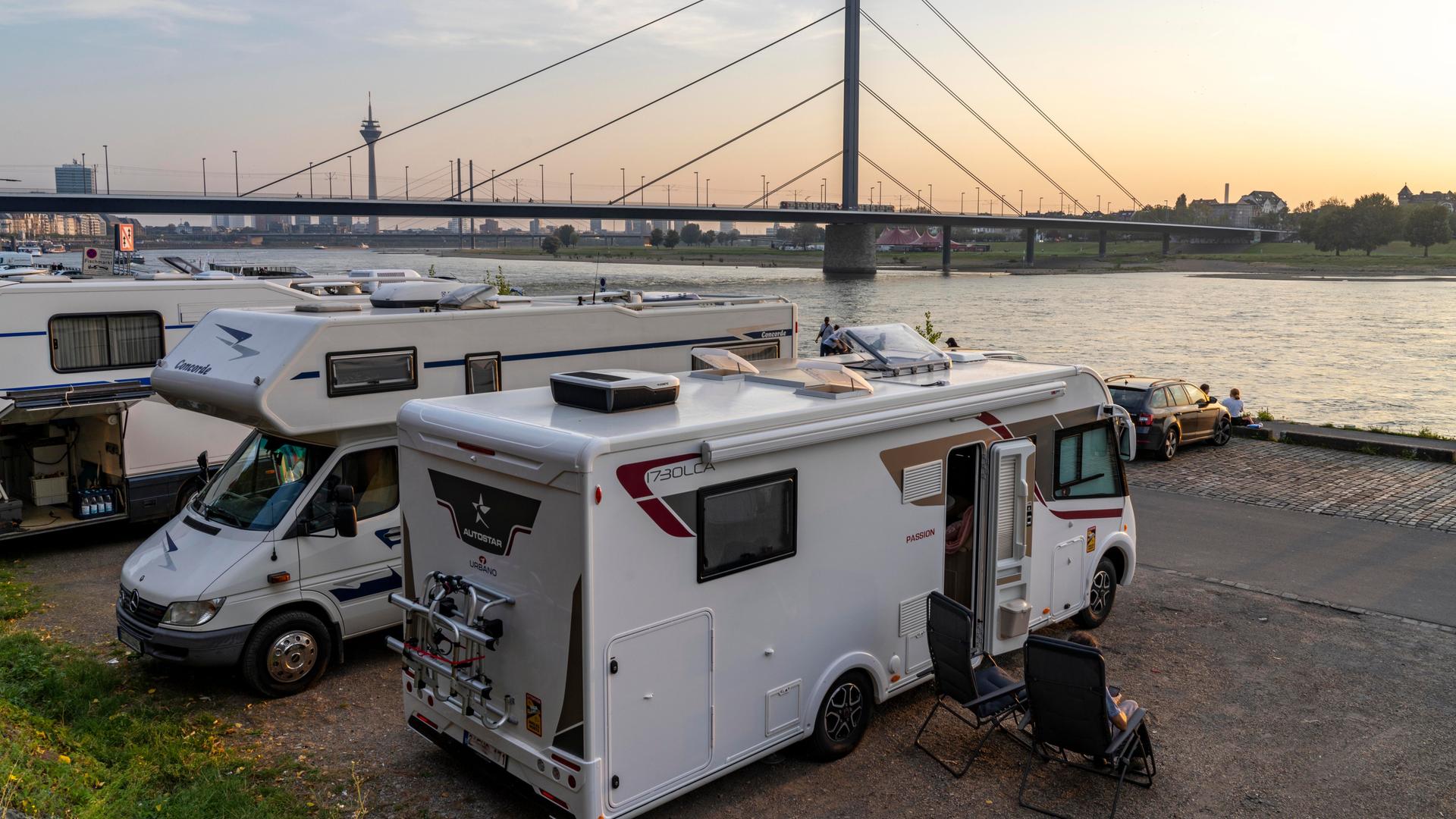 Ein Wohnmobil-Stellplatz am Rheinuferr in Düsseldorf, im Hintergrund eine Brücke