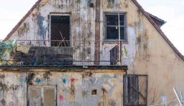 Frontalansicht der Fassade eines Hauses im desolaten Zustan, das mit zahlreichen Farbbeutel beworfen wurde.