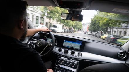 Ein Fahrer fährt in einem Taxi, das auch über Uber und Bolt gebucht werden kann.