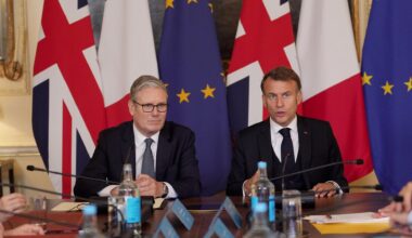 Der britische Premierminister Starmer und Frankreichs Präsident Macron sitzen nebeneinander, hinter ihnen die Landes- und die EU-Flagge.