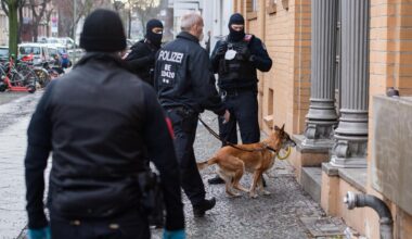 Berlin: Polizisten gehen bei einer Razzia mit einem Hund in ein Haus.