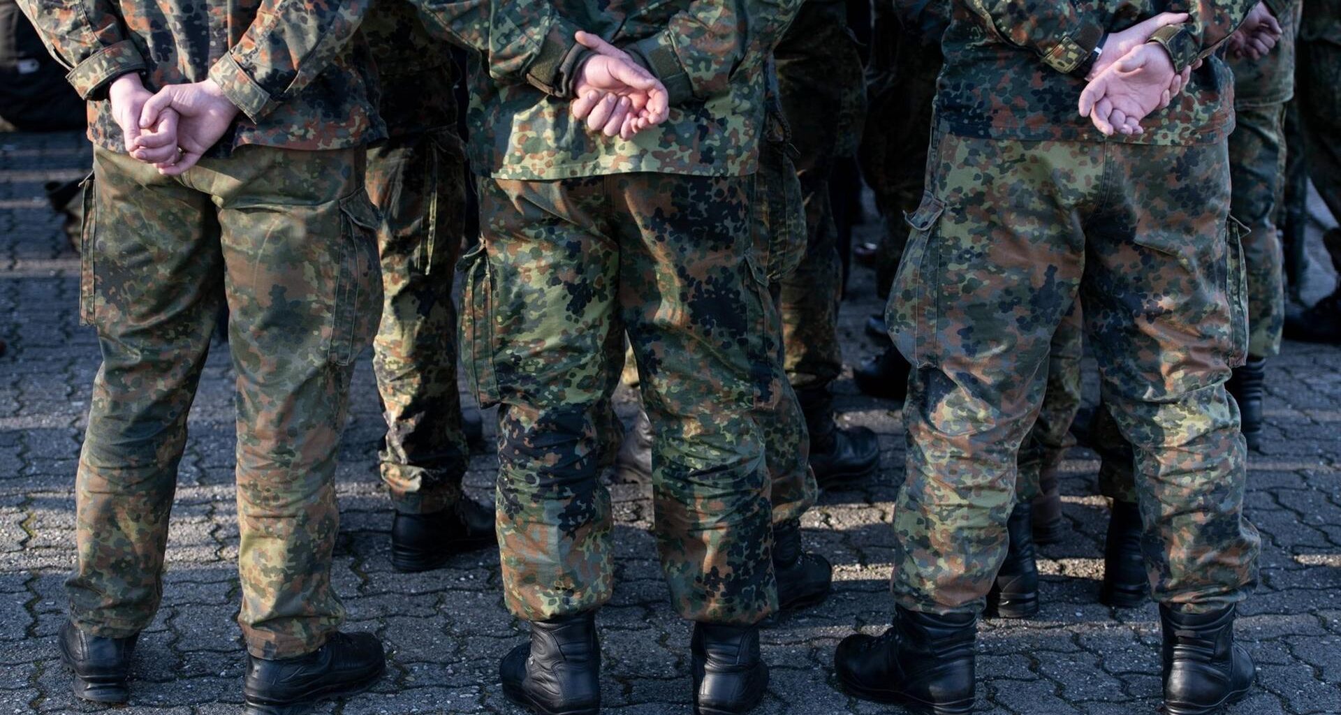 Mehrere Soldaten der Bundeswehr in Uniform von hinten mit den Händen auf dem Rücken