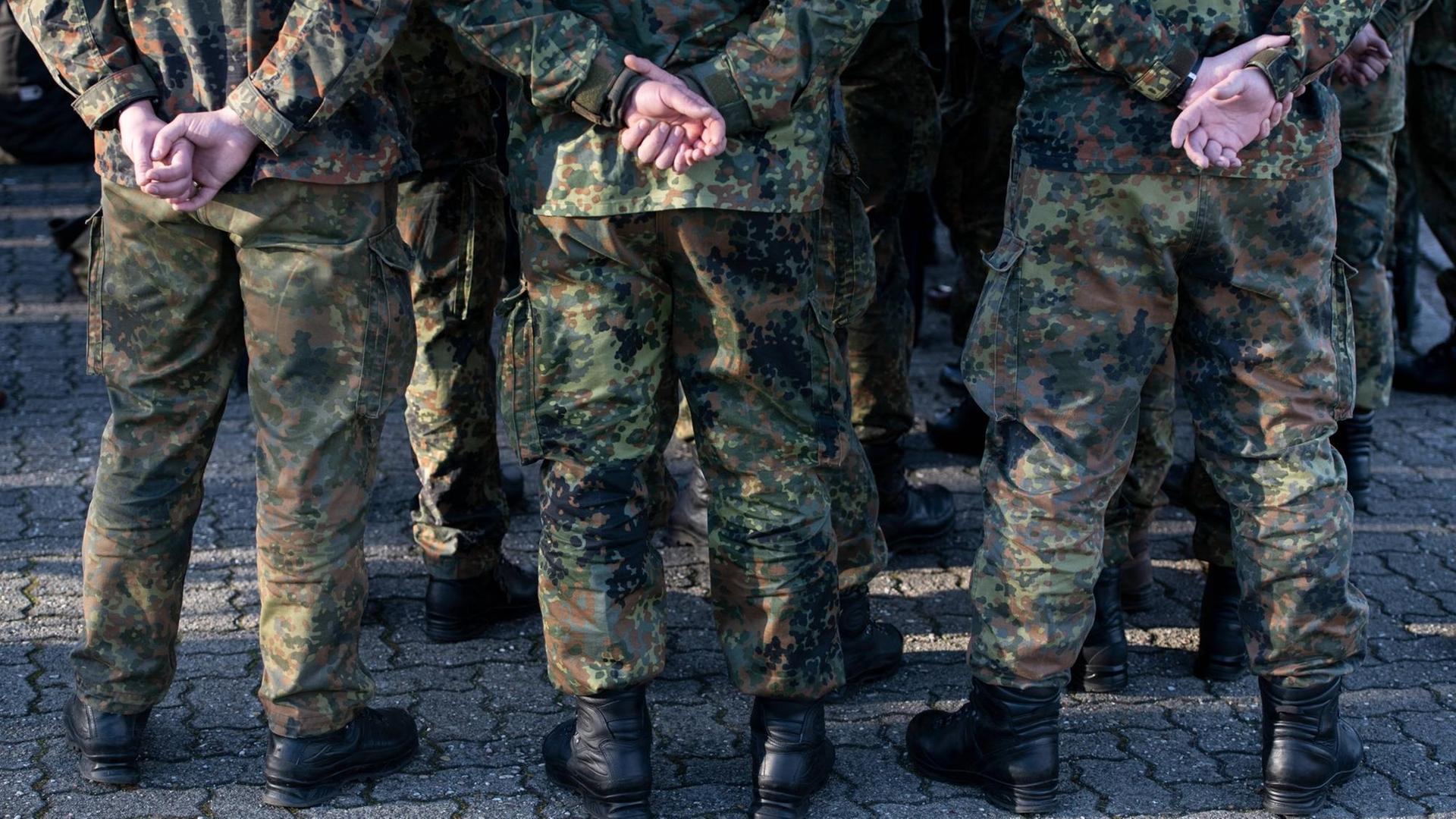 Mehrere Soldaten der Bundeswehr in Uniform von hinten mit den Händen auf dem Rücken